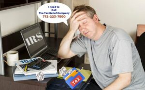 Tips for the Tax Procrastinator- man at computer with eyes closed and tax folders and crumbled papaer.